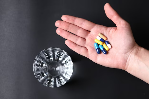 Medical pills in a person's hand and a glass of water. view from above