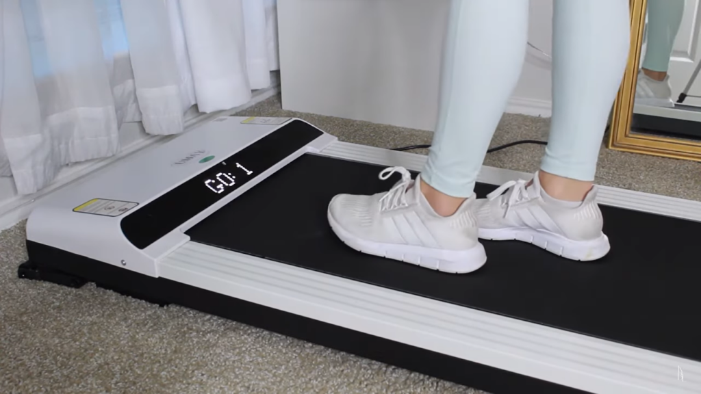 woman in bright blue leggings and white sneakers on black and white treadmill