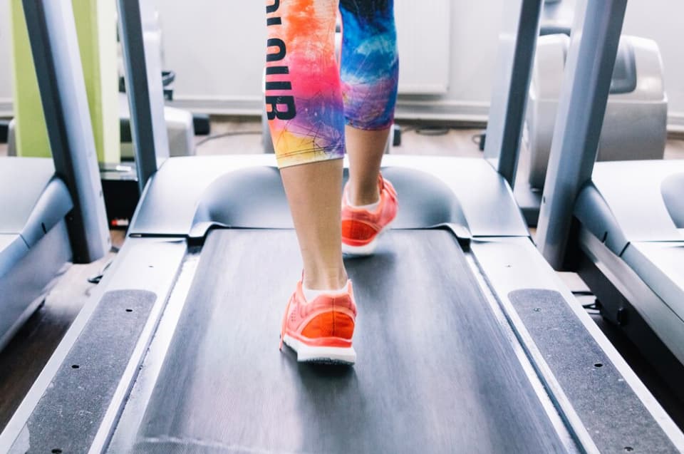 woman in colorful legging and yellow sneakers on a treadmill