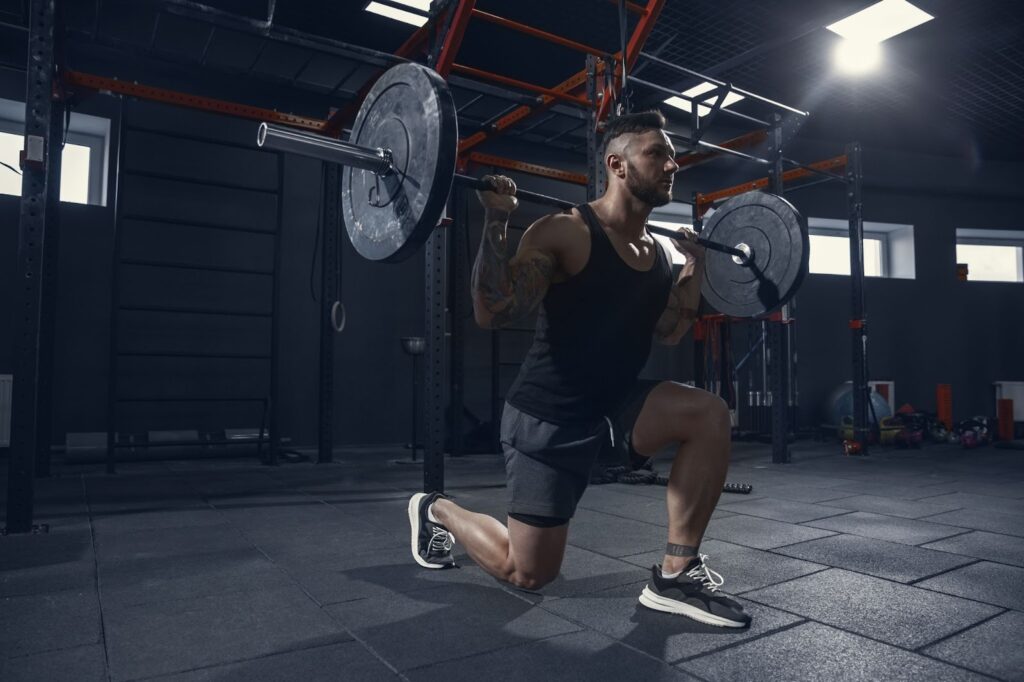 Athlete practicing lunges in gym with barbell